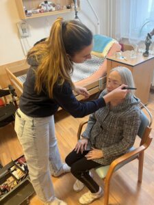 Studentky při líčení a česání seniorů.